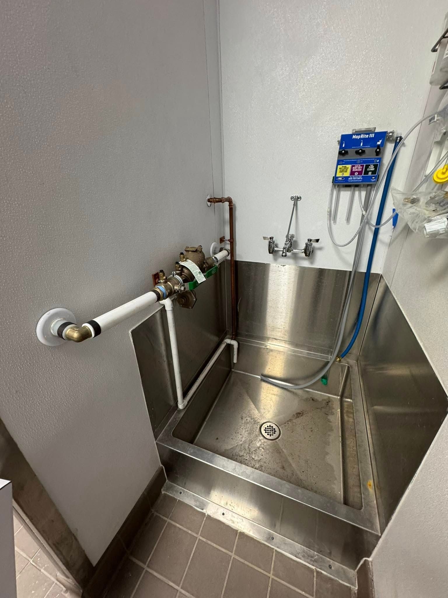 A stainless steel sink with a hose attached to it in a bathroom.