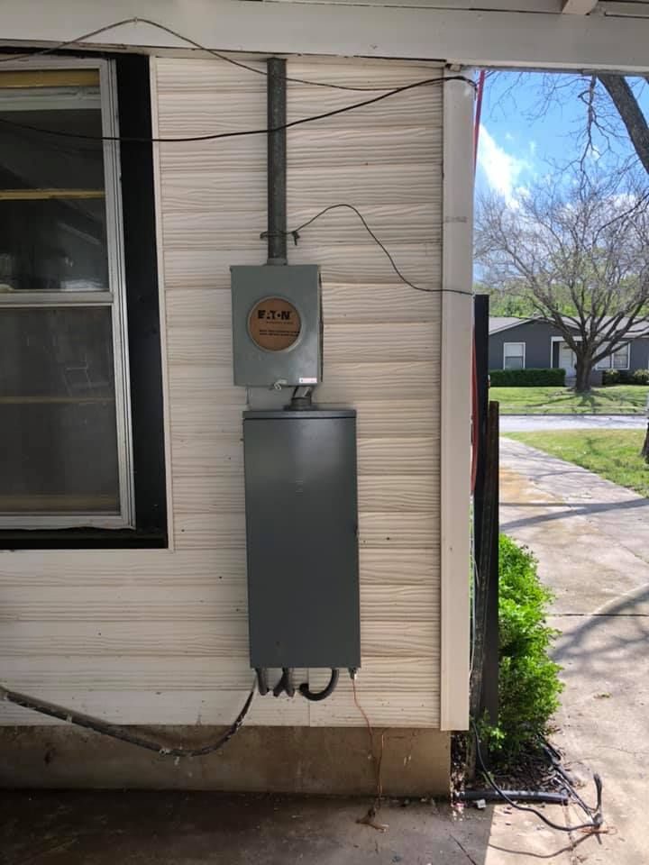 A electrical box is attached to the side of a house.