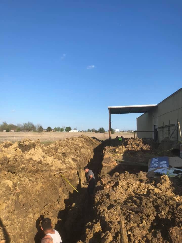 A man is digging a hole in the dirt in front of a building.
