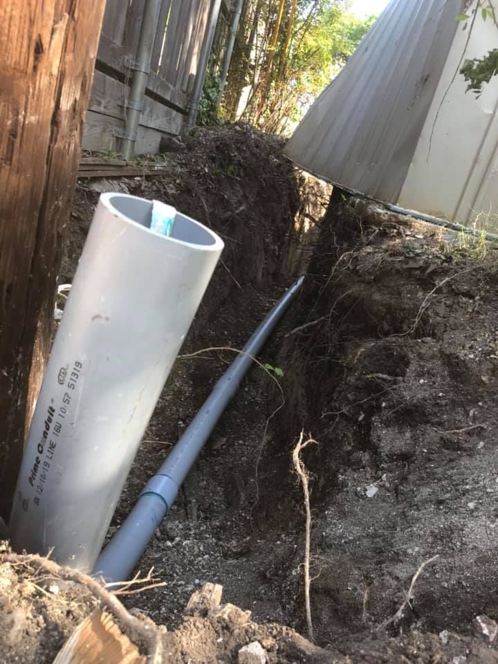A pipe is laying in the dirt next to a fence.