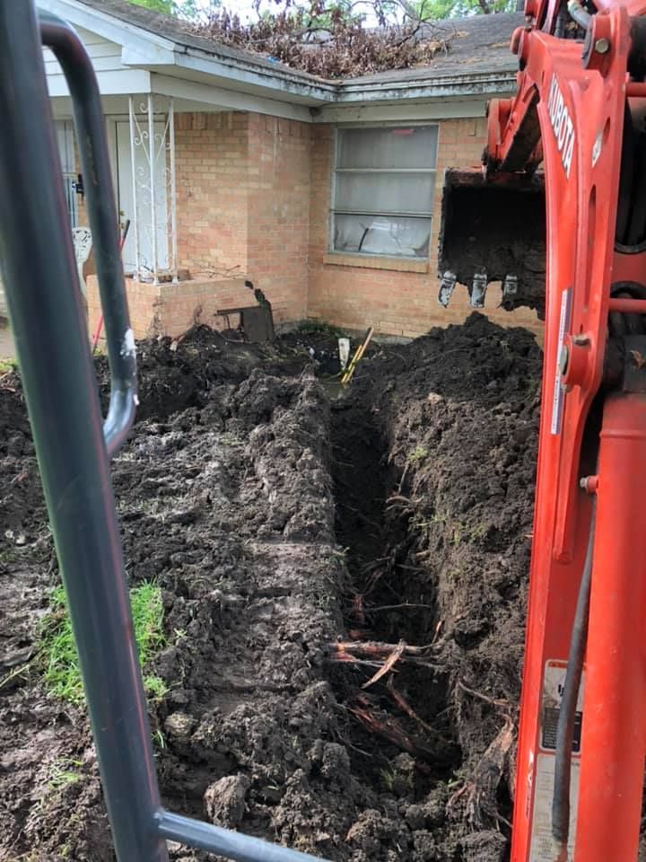 An excavator is digging a hole in front of a house.