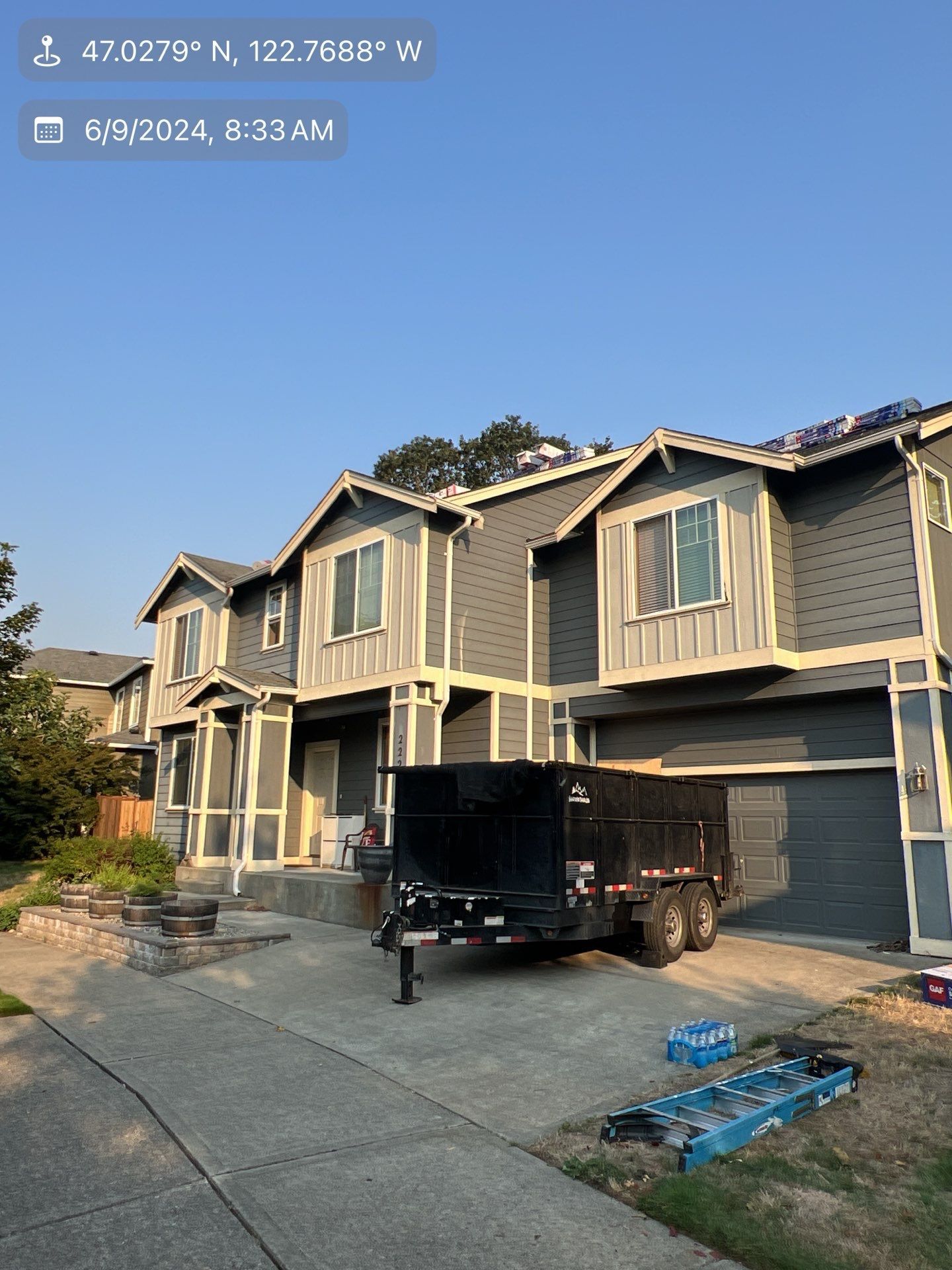 Townhouses with gray siding, parked trailer, blue sky.
