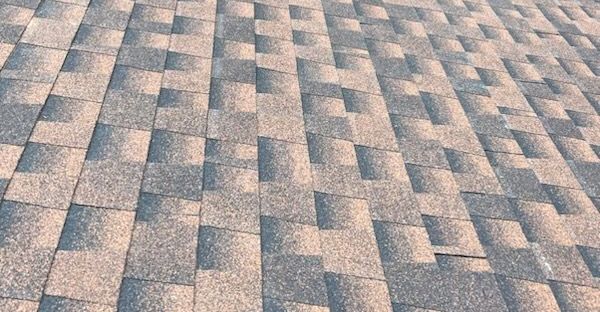 Close-up of a shingled roof with a GAF  neutral color pattern and visible texture.