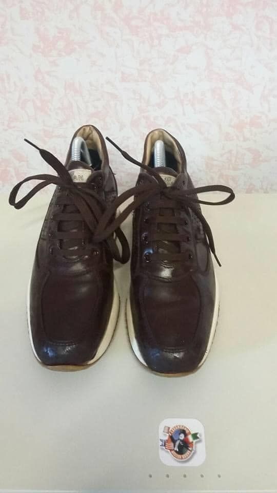 Un paio di scarpe da ginnastica in pelle marrone sono appoggiate su un tavolo bianco.