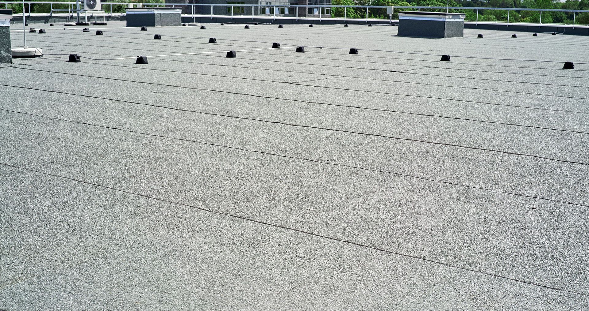 A construction worker is working on a roof with a drill.