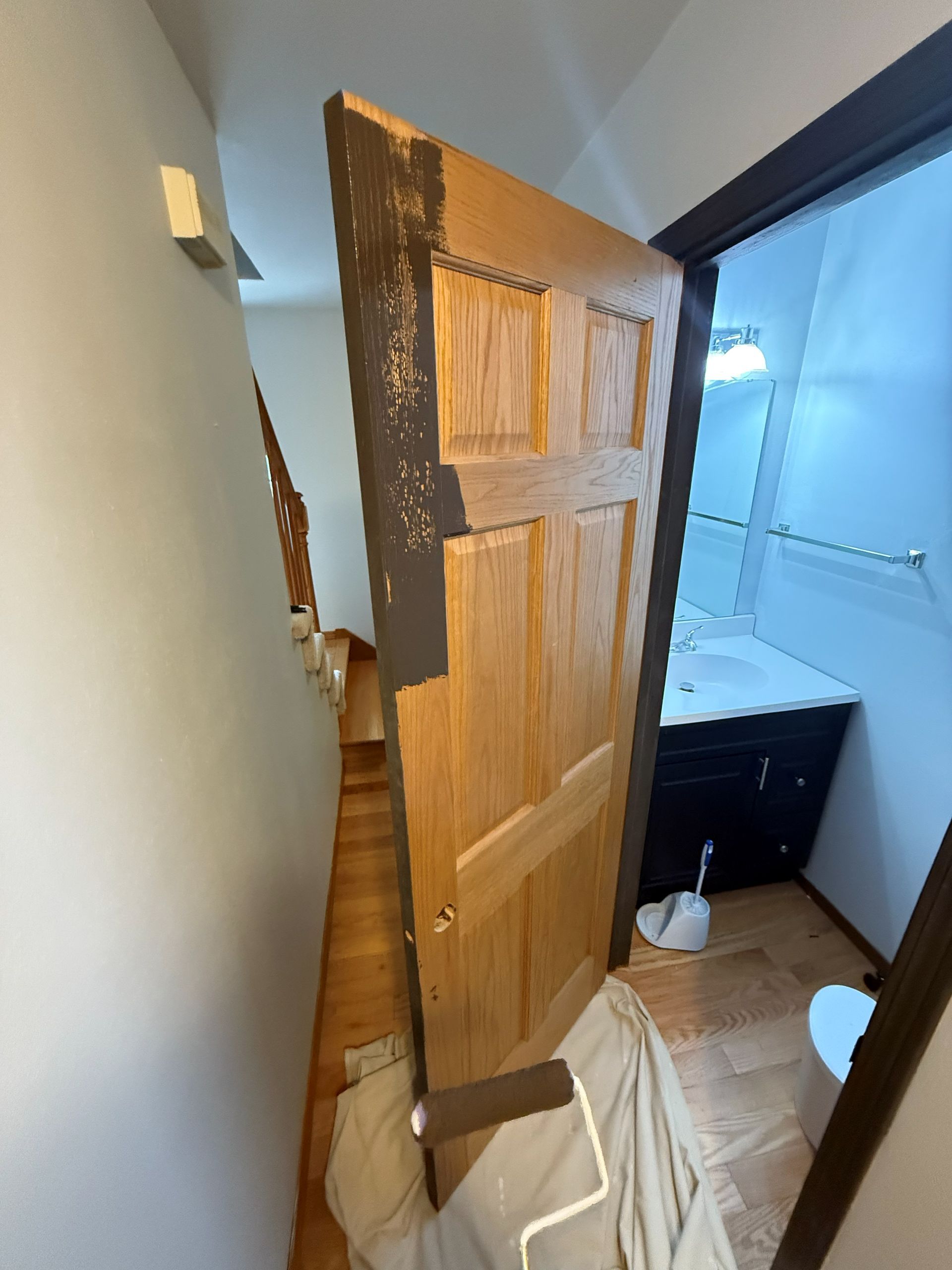 Woman in straw hat smiles, holding wine glass near a lake.