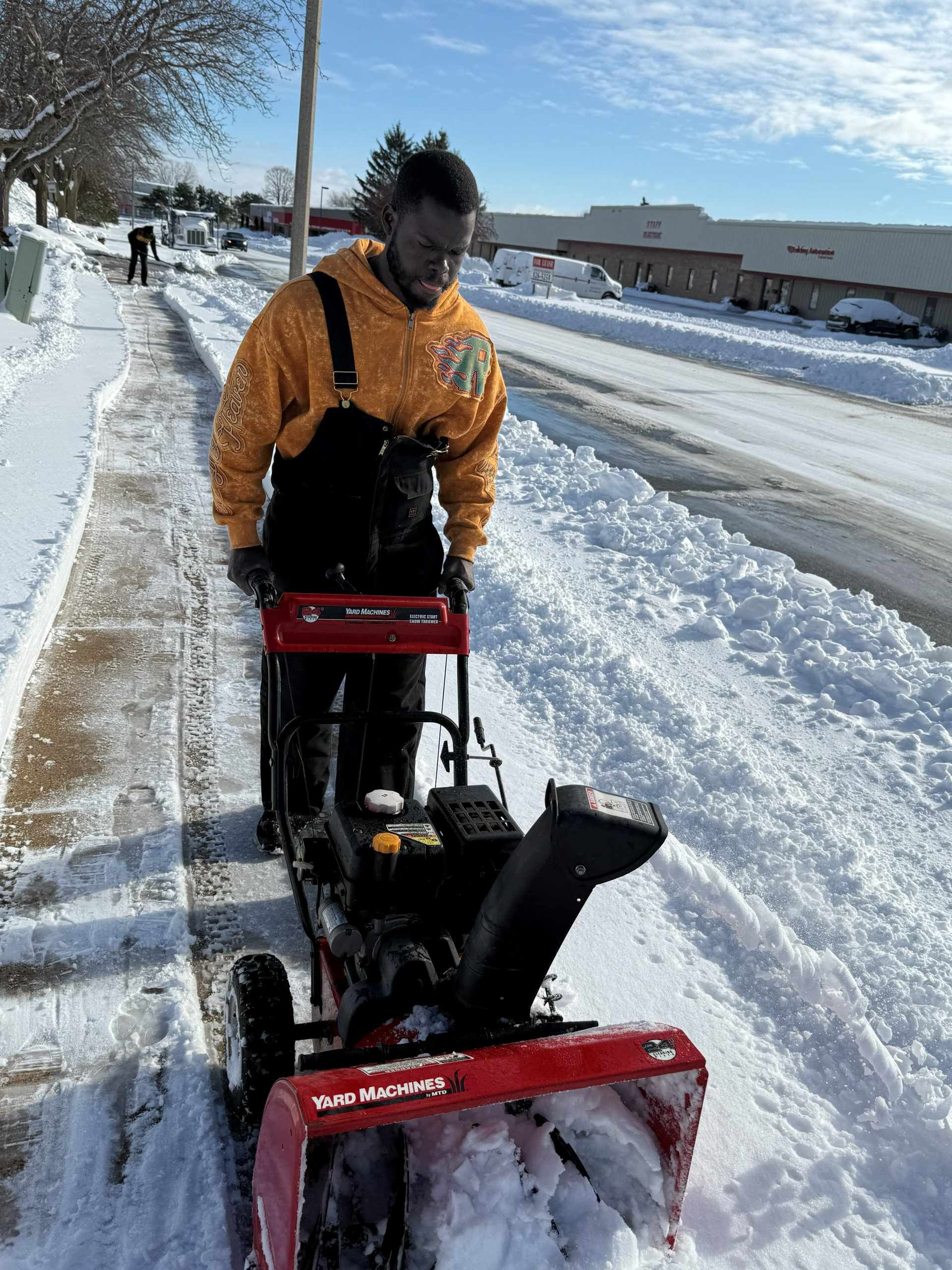 Woman in straw hat smiles, holding wine glass near a lake.