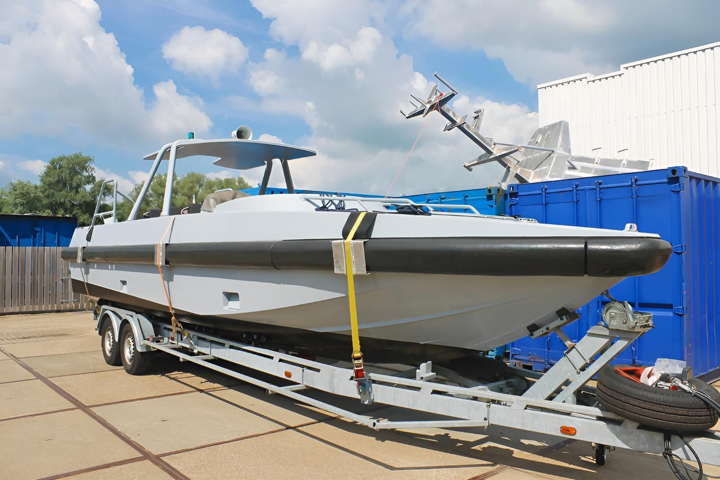 A boat is sitting on a trailer in front of a blue container — BCV Storage Centre in Wauchope, NSW