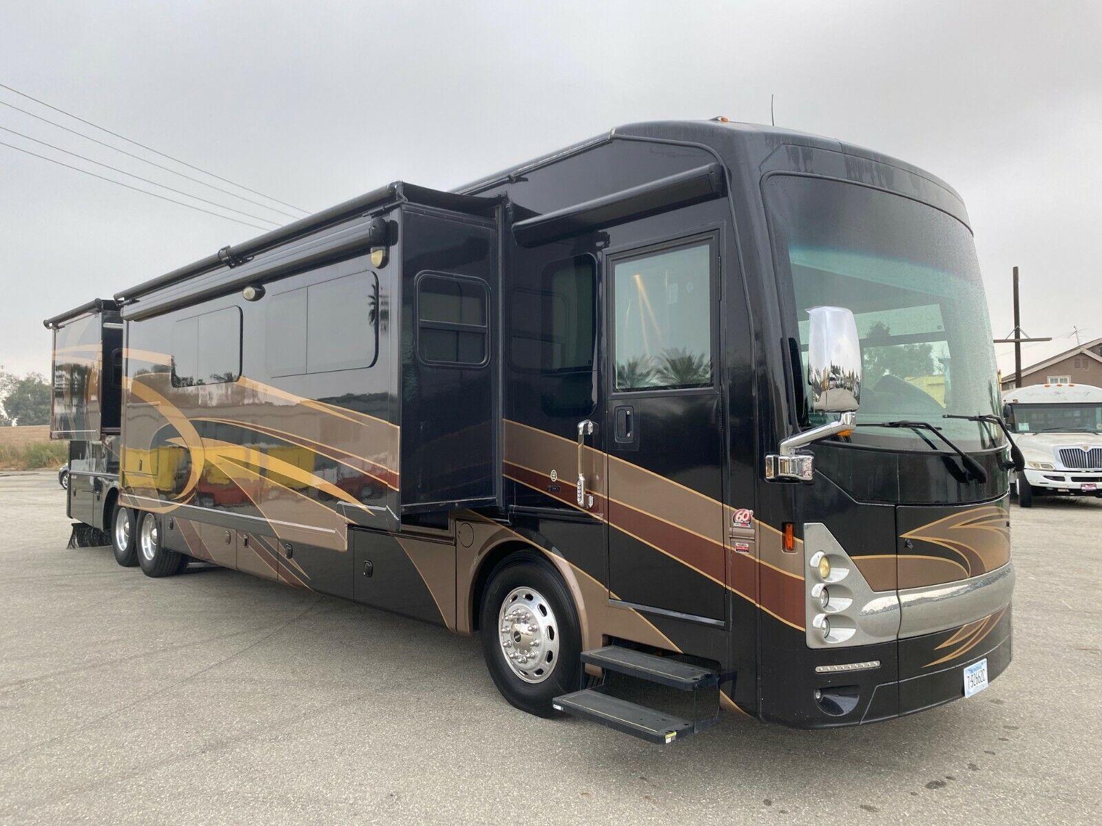 A large black and brown rv is parked in a parking lot.