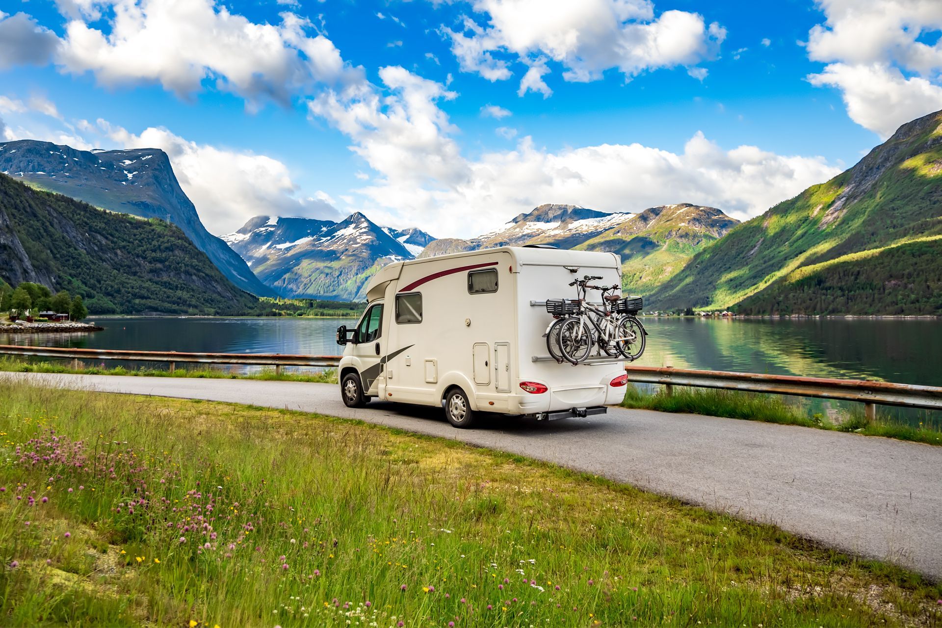 RV on Road With Lake and Mountains in Background
