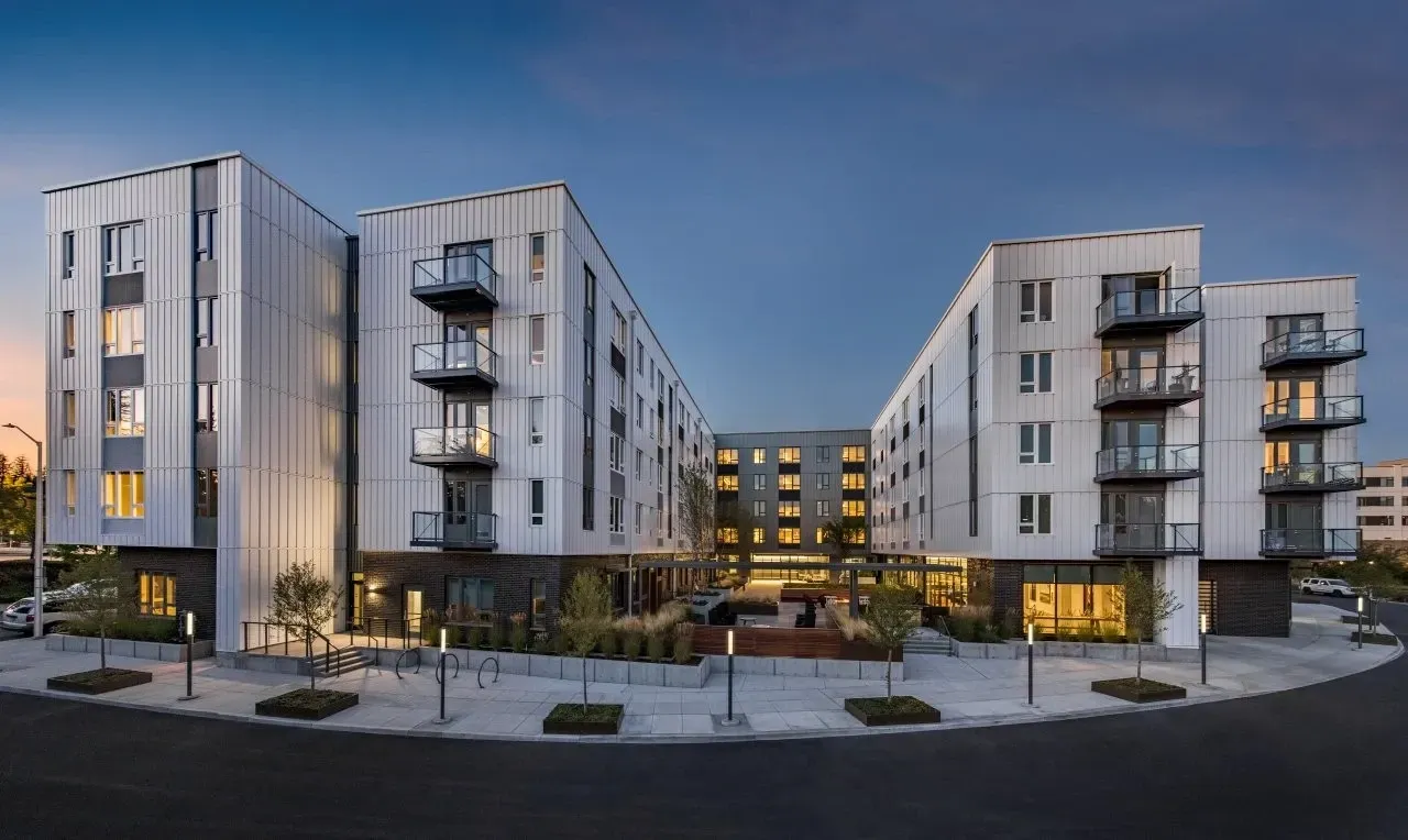 Modern apartment building exterior with balconies and courtyard, twilight.