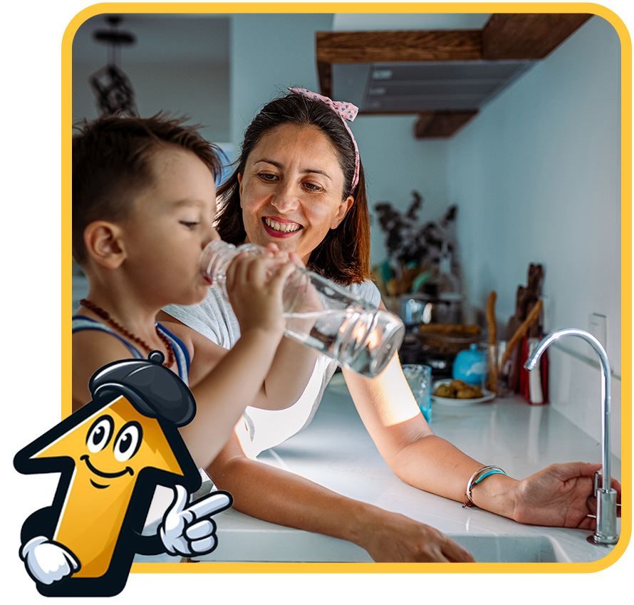 Woman helps child drink water from a bottle in a kitchen.