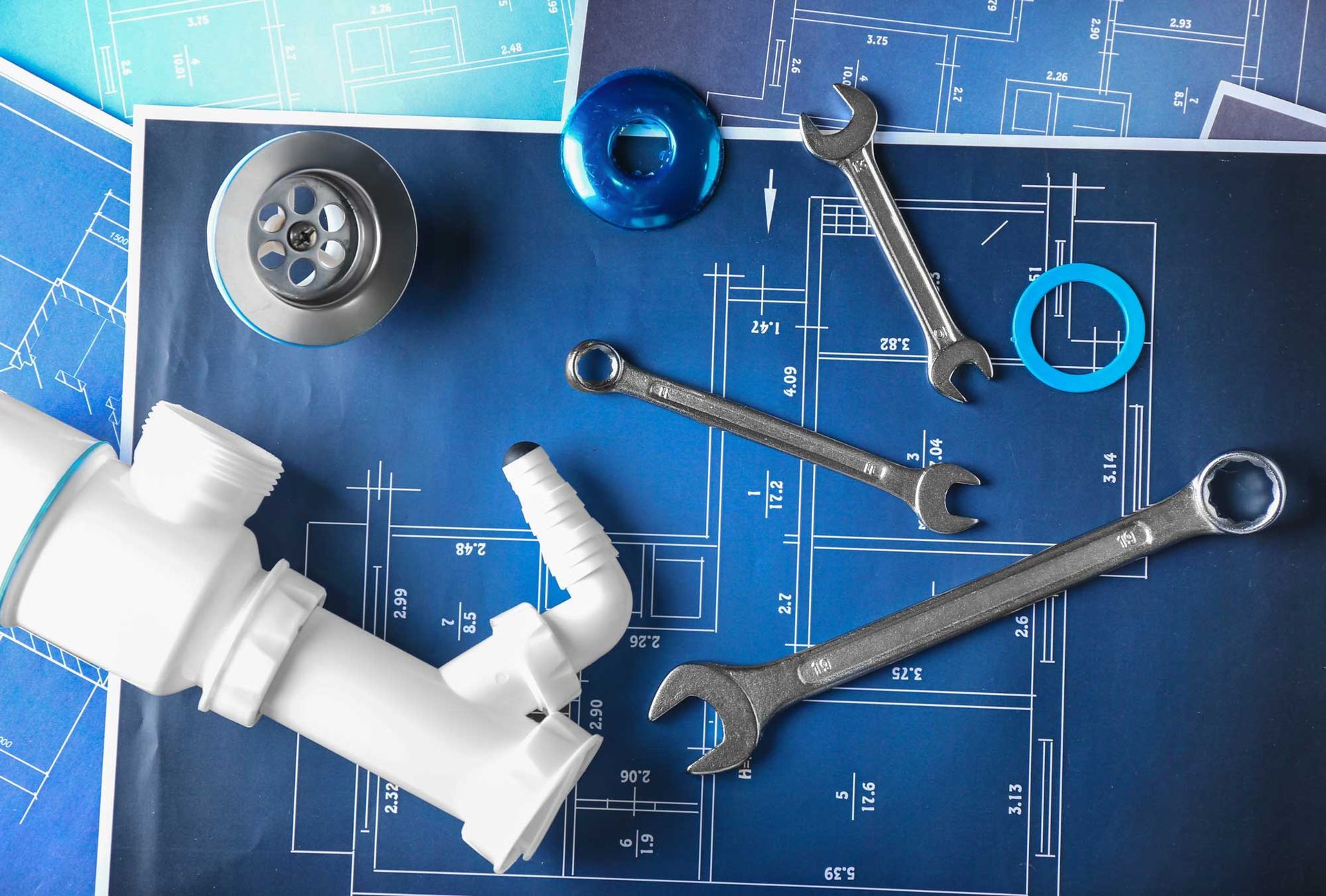 Plumbing tools on a blueprint, showcasing planning details for commercial plumber service.