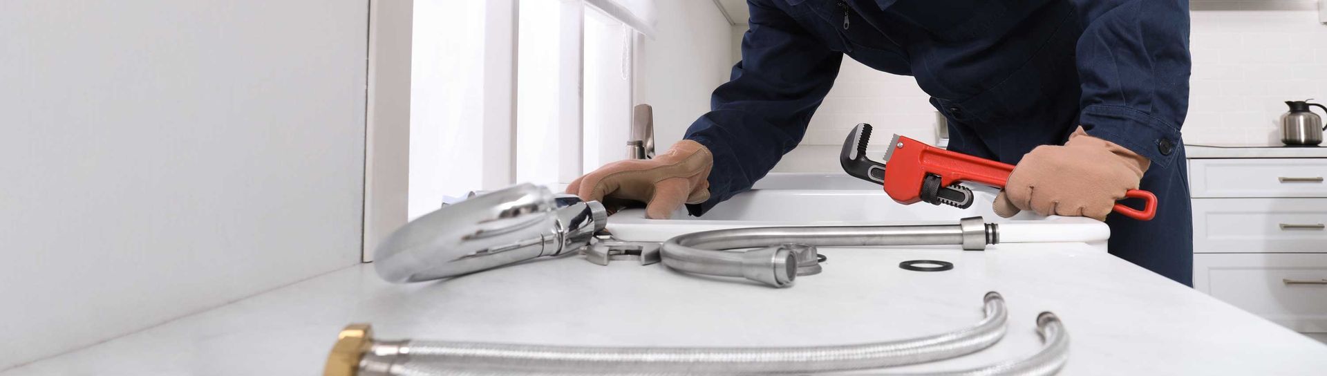 Plumber repairing a kitchen sink faucet, showcasing precision in commercial plumber service.