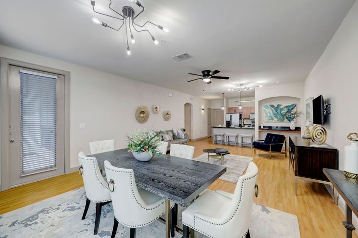 Dining room with a gray table, white chairs, and open to the living area.