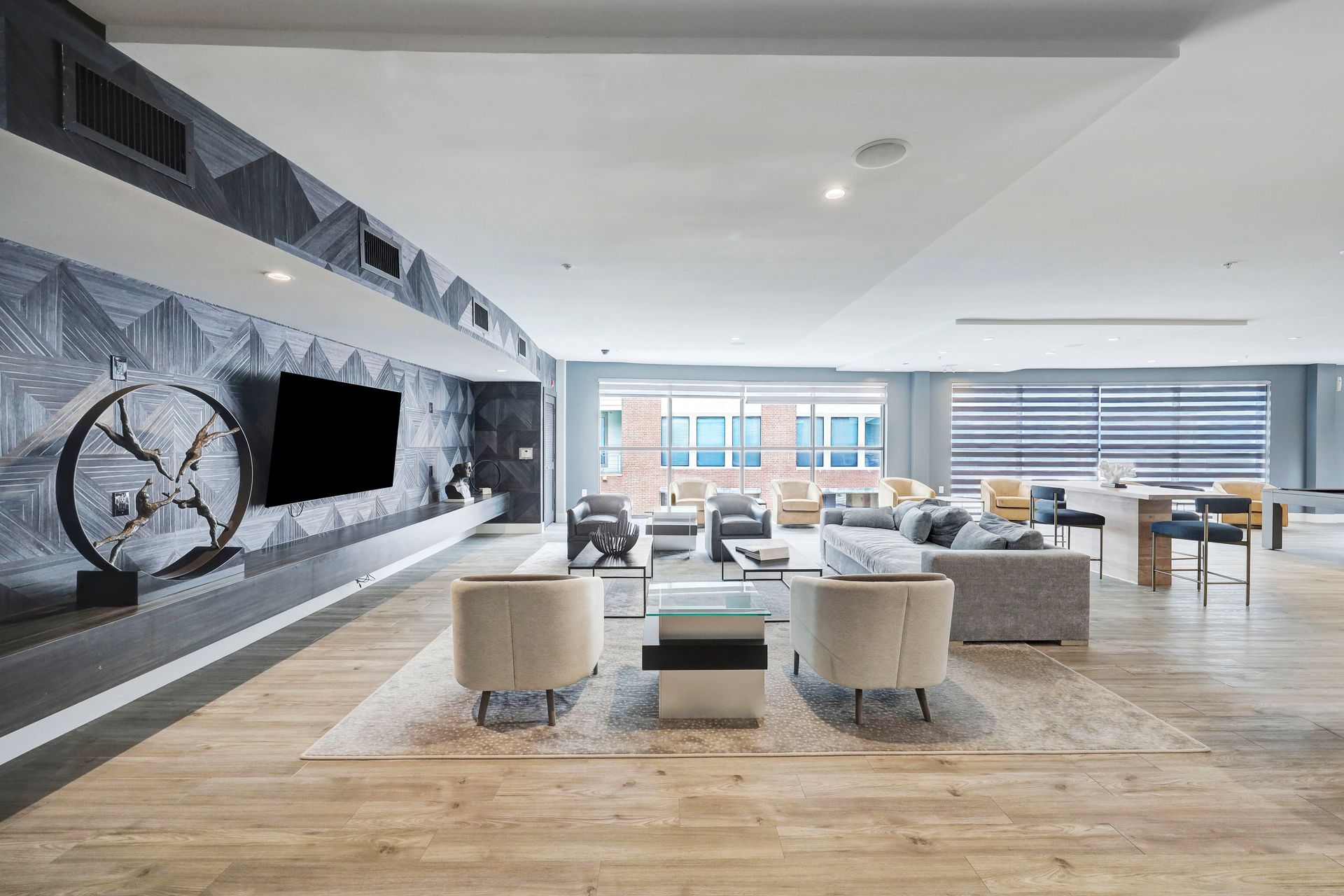 Modern apartment lounge with seating, TV, art, and large windows.