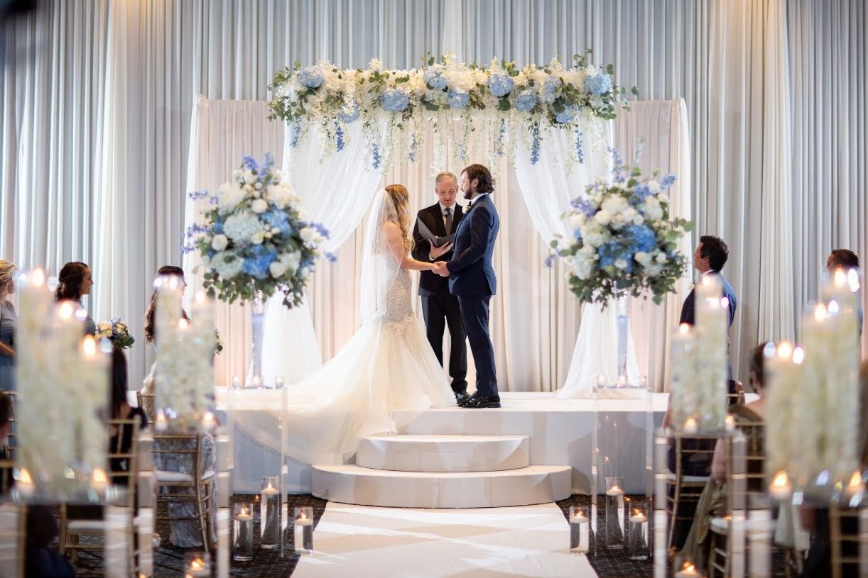 A bride and groom are holding hands during their wedding ceremony.