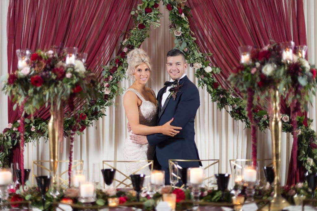 A bride and groom are posing for a picture at their wedding reception.