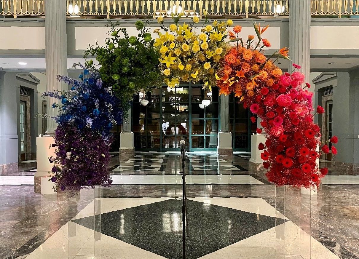 A rainbow of flowers is displayed in a lobby of a building.