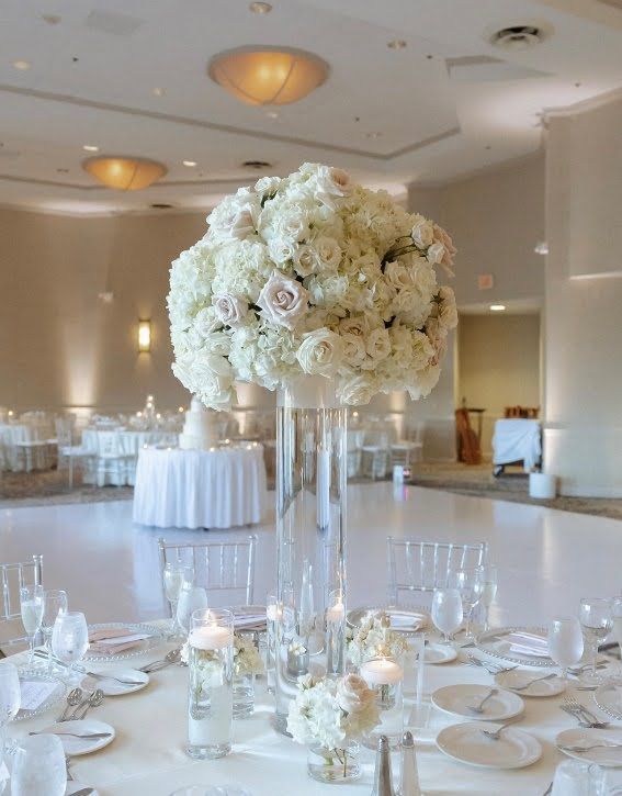 A large vase filled with white flowers sits on a table