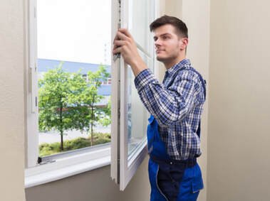 Picture of a window installer installing new white windows on a hinge.  The windows are white and were purchased at a window store.  The window is in Belleville.