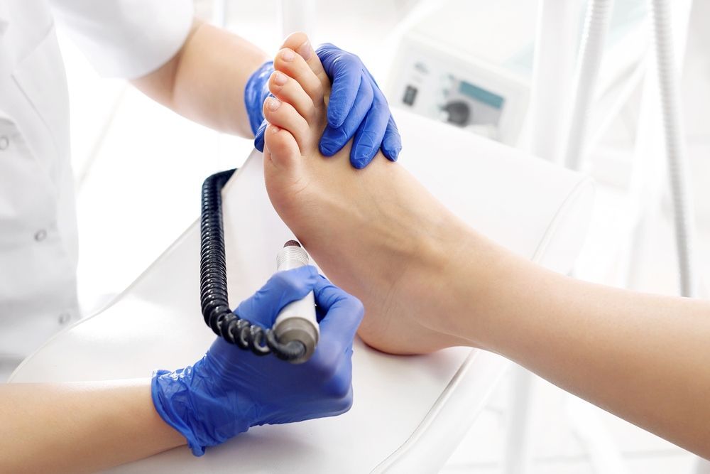 A Woman is Getting Her Feet Examined by a Podiatrist — Craig Hughes Podiatry in Mount Hutton, NSW