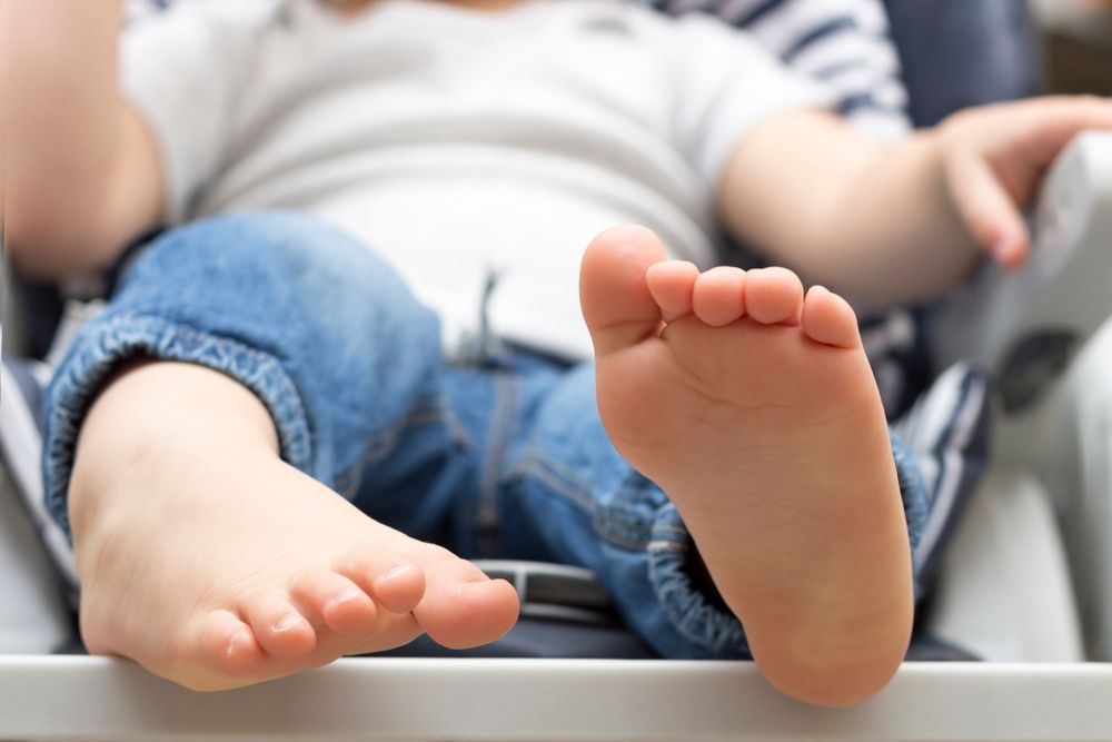 A Baby's Feet Are Laying on a High Chair — Craig Hughes Podiatry in Mount Hutton, NSW