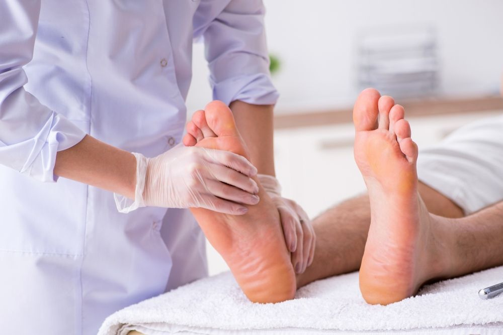 A Nurse is Examining a Patient's Foot in a Hospital — Craig Hughes Podiatry in Mount Hutton, NSW