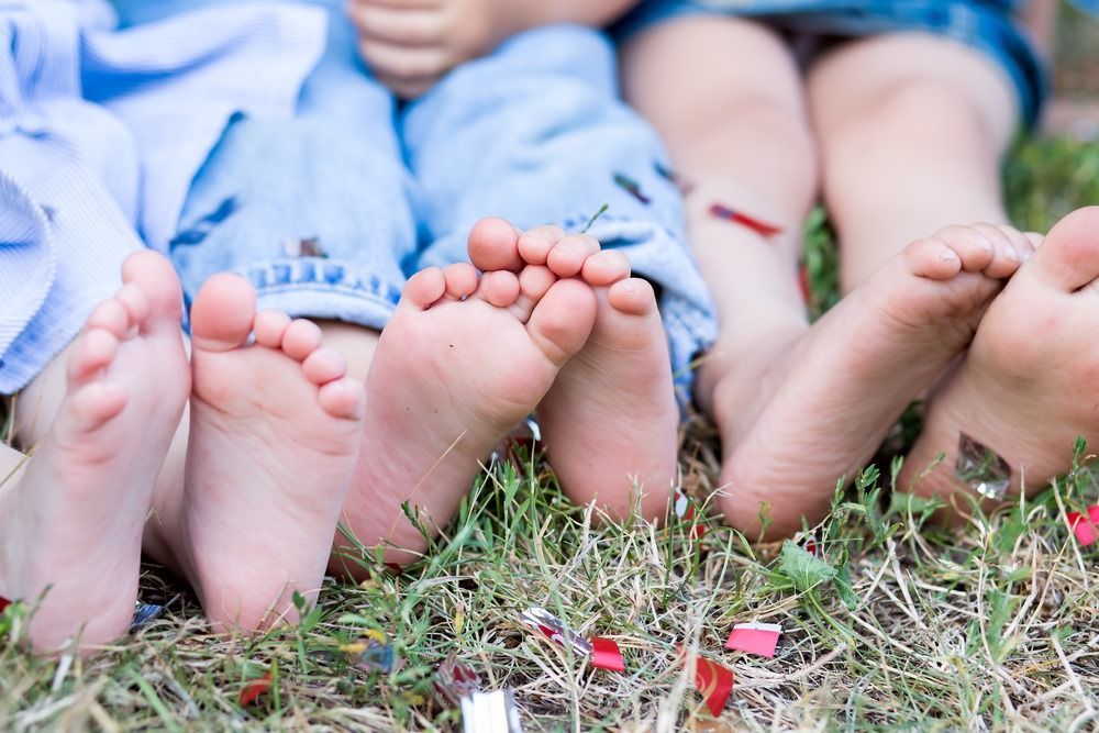A Group of Children's Feet Are Laying in the Grass — Craig Hughes Podiatry in Mount Hutton, NSW