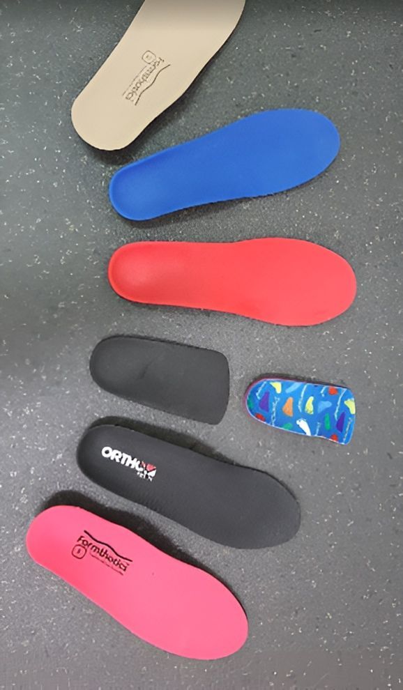 A Bunch of Different Types of Insoles Are Lined Up on a Table — Craig Hughes Podiatry in Mount Hutton, NSW