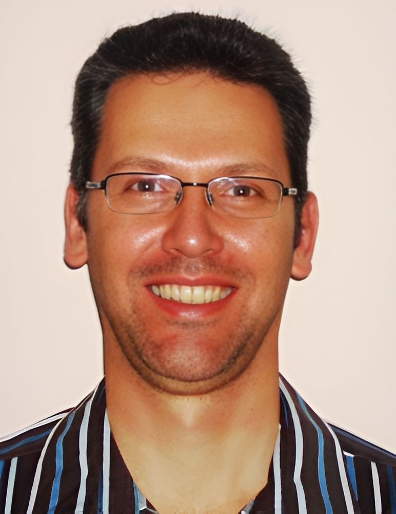 A Staff Wearing Glasses and a Striped Shirt Smiles for the Camera — Craig Hughes Podiatry in Mount Hutton, NSW