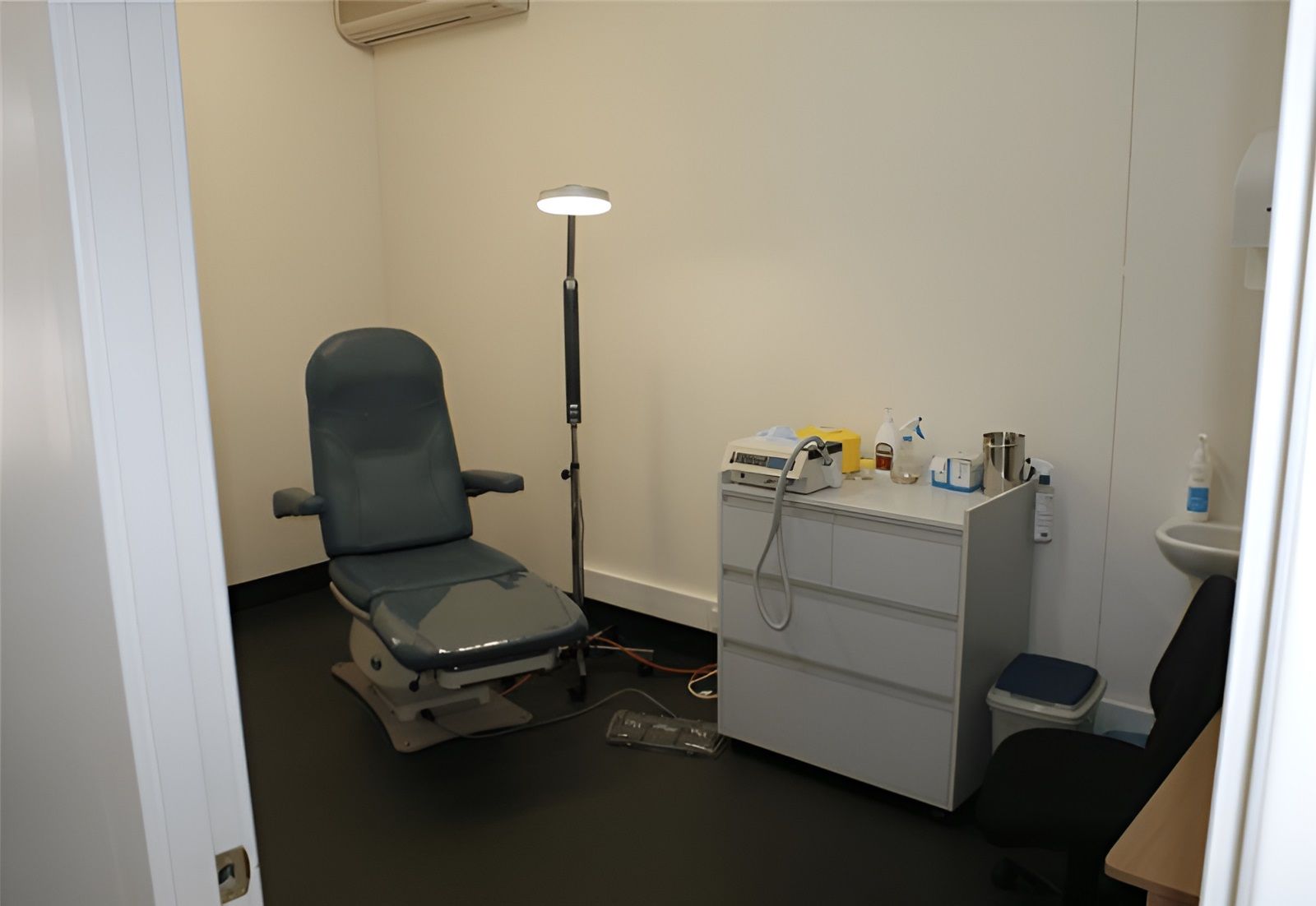 A Doctor's Office With a Chair and a Sink — Craig Hughes Podiatry in Mount Hutton, NSW