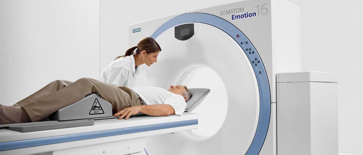 Un hombre está acostado en una cama y le están haciendo una tomografía computarizada.