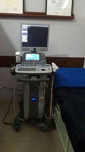 Una máquina de ultrasonido está en una habitación al lado de una cama.