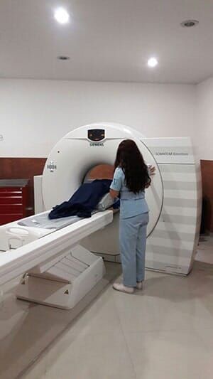 Una mujer está parada frente a una máquina de tomografía computarizada.