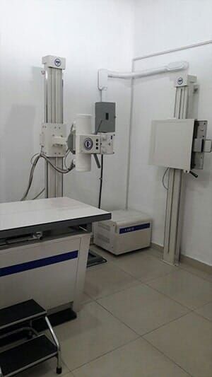 Una máquina de rayos X está en una habitación al lado de una mesa.