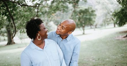 A man and a woman are standing next to each other in a park.