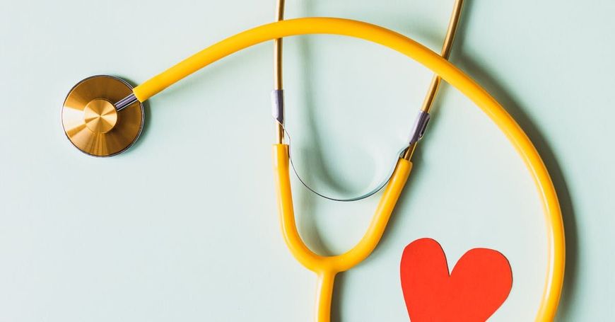 A yellow stethoscope with a red heart attached to it.