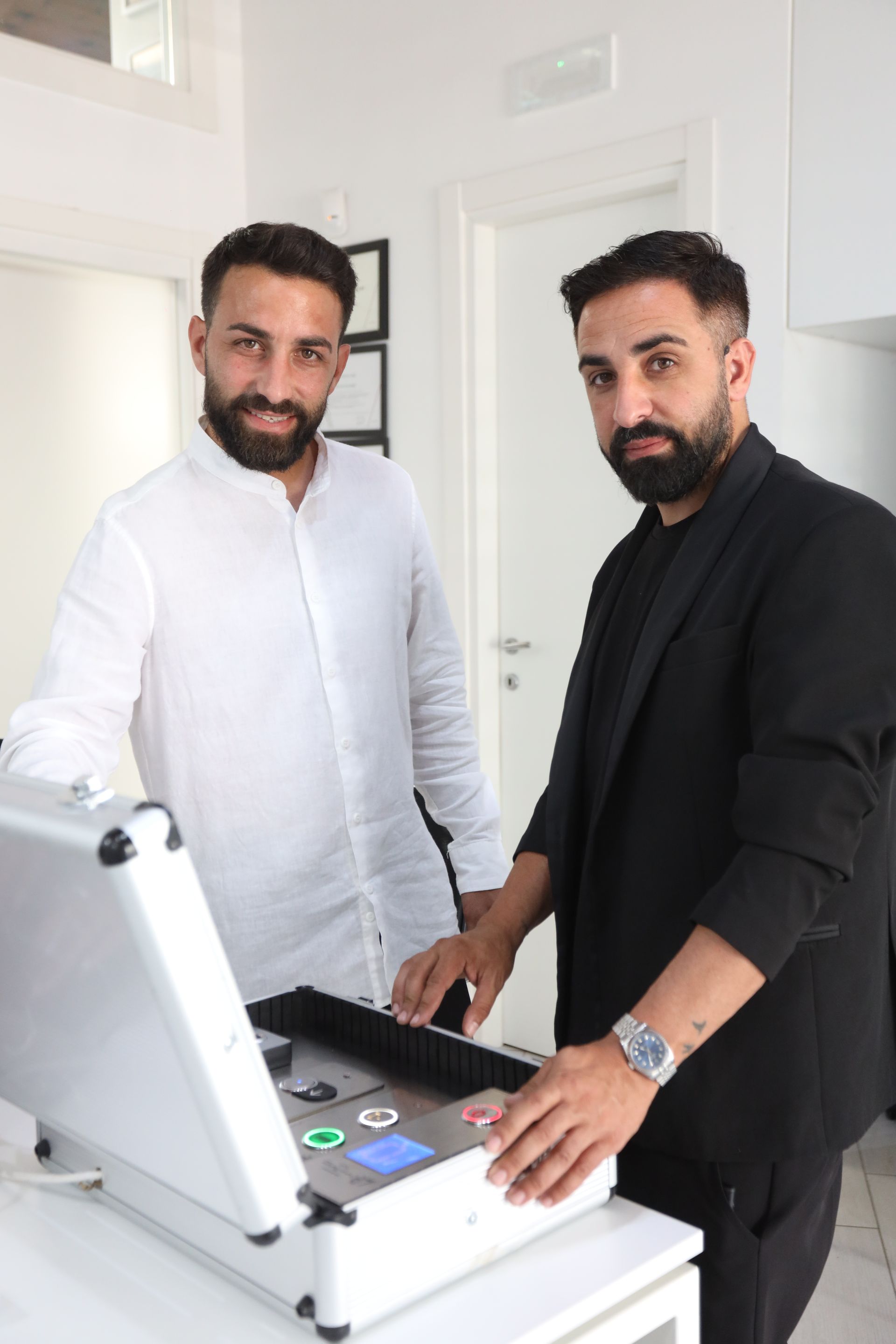 Due uomini sono in piedi uno accanto all'altro davanti a una macchina.