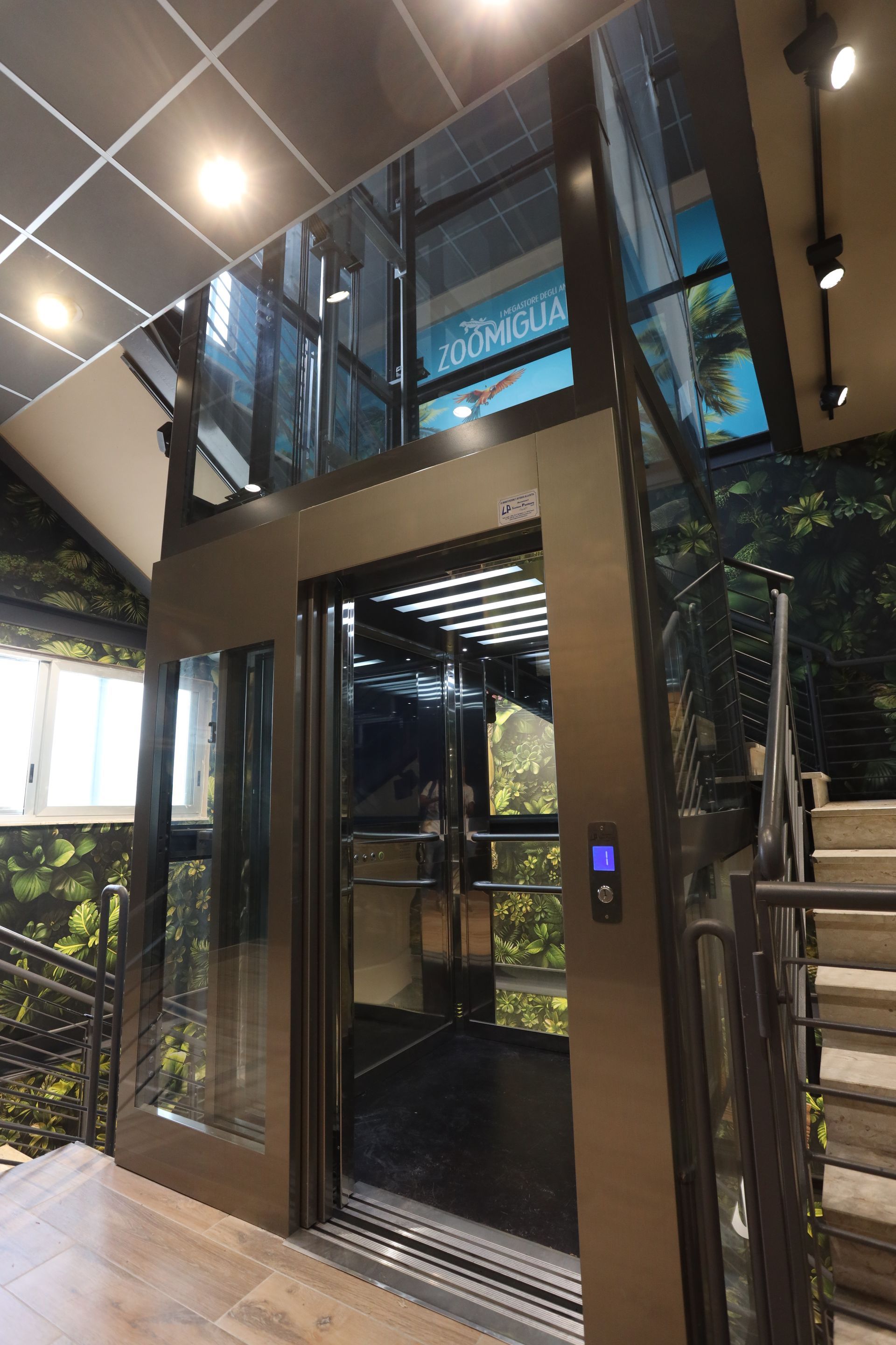 Un ascensore con porta a vetri e scale in un edificio.