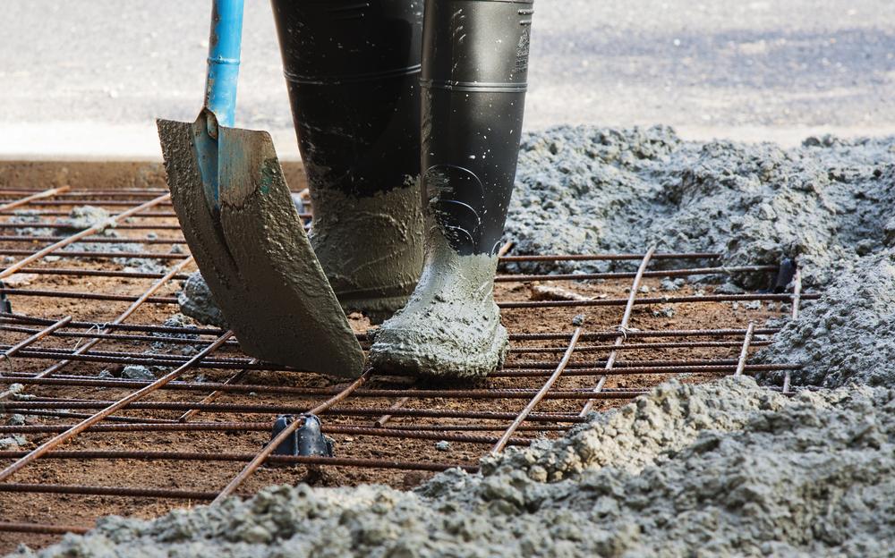 Person With Gum Boots Spreading Ready Mix Concrete — Concreting Works in Medowie, NSW