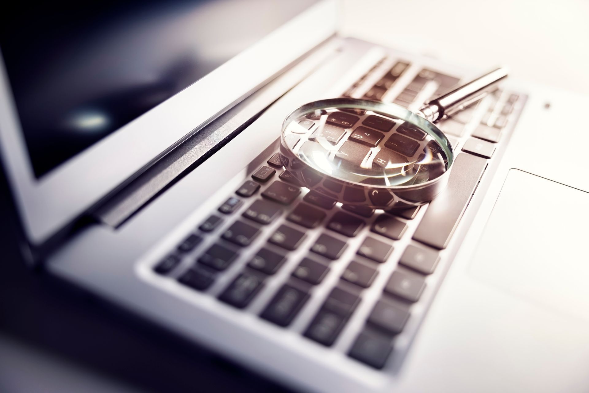 A magnifying glass is sitting on top of a laptop keyboard.