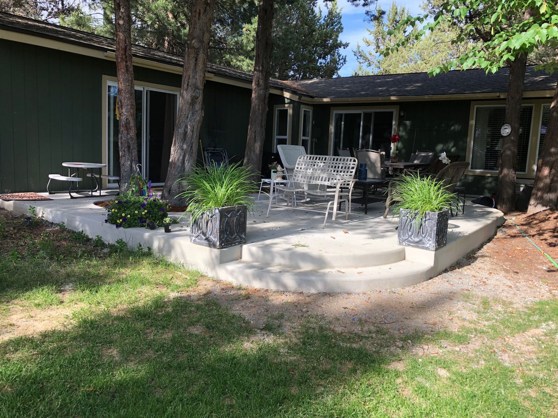 A patio with a bench and chairs in front of a house.