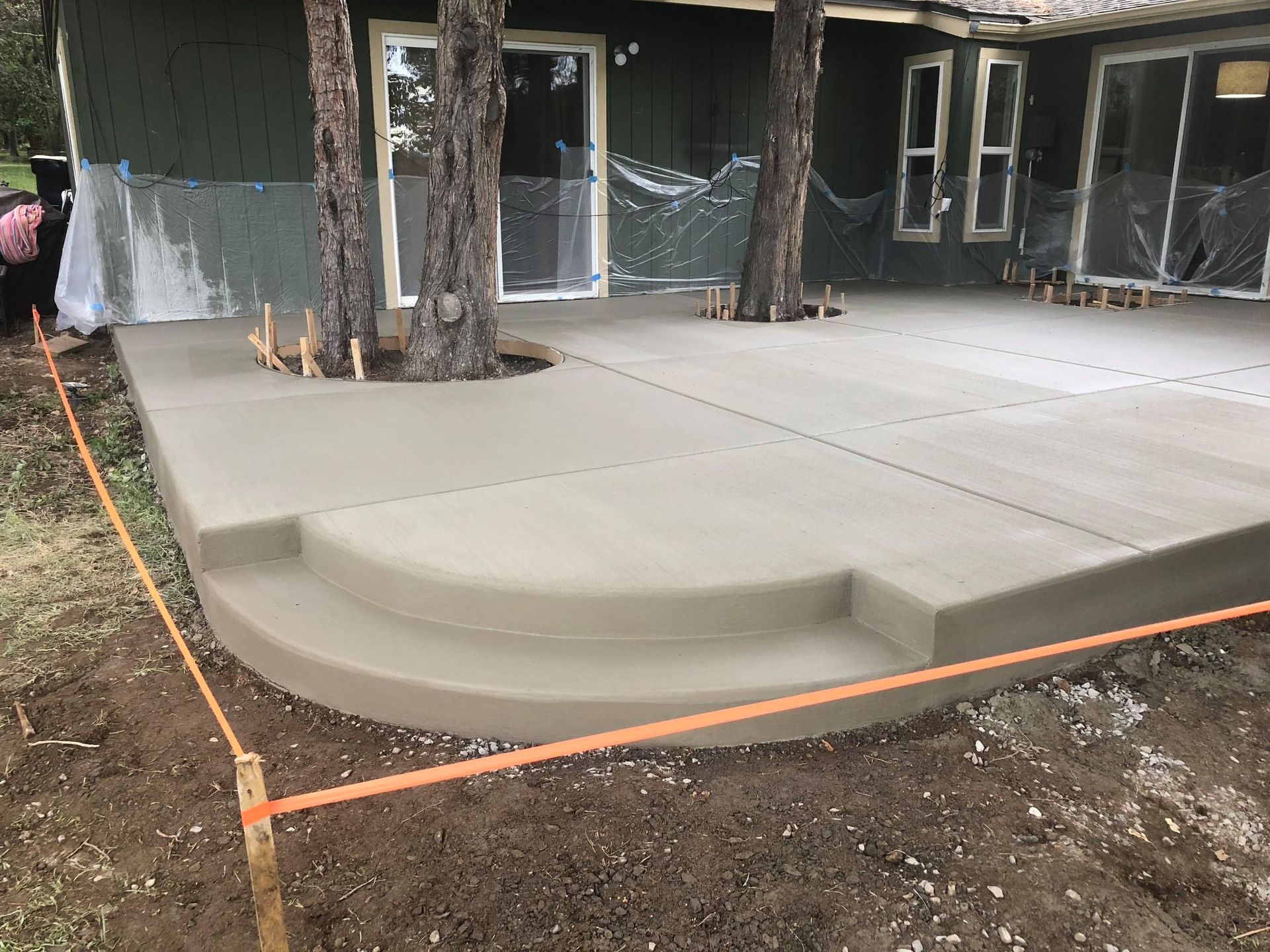 A concrete patio is being built in front of a house.