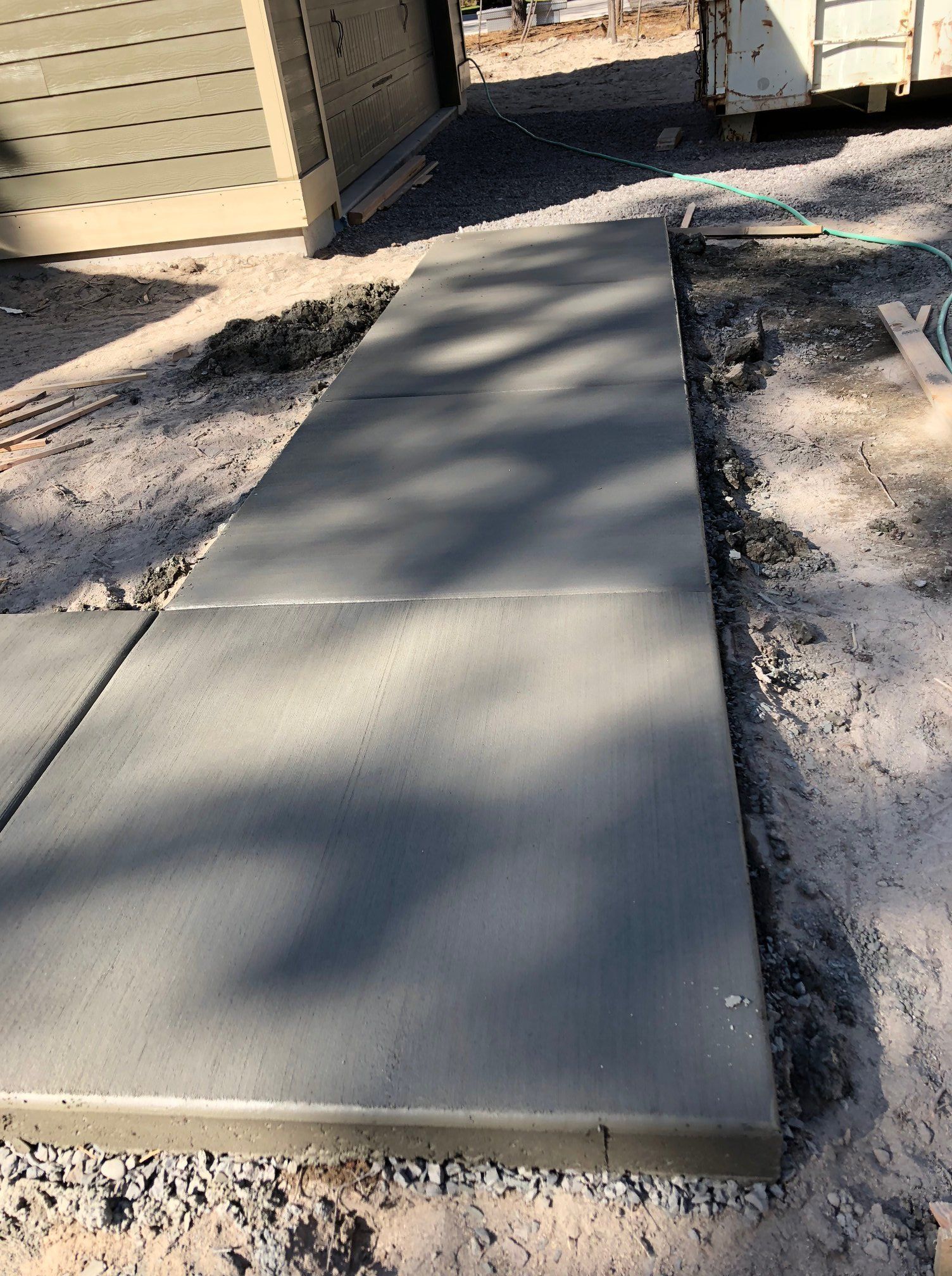 A concrete walkway is being built in front of a garage.