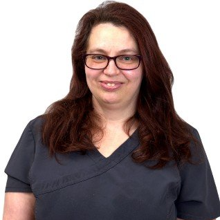 A woman wearing glasses and a scrub top is smiling for the camera.