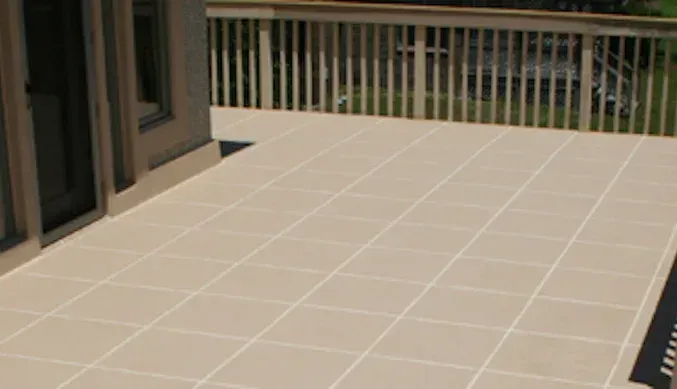 A tiled deck with a railing and a rug on it.