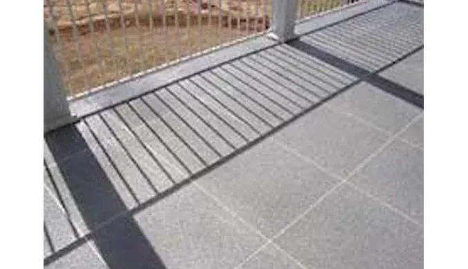 A close up of a tiled floor next to a fence.