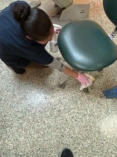 A woman is cleaning a dental chair in a dental office.