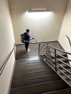 A man is cleaning the stairs with a vacuum cleaner.